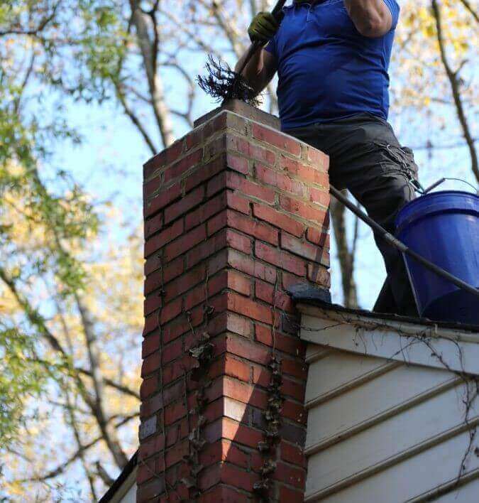 Technician sweeping a chimney
